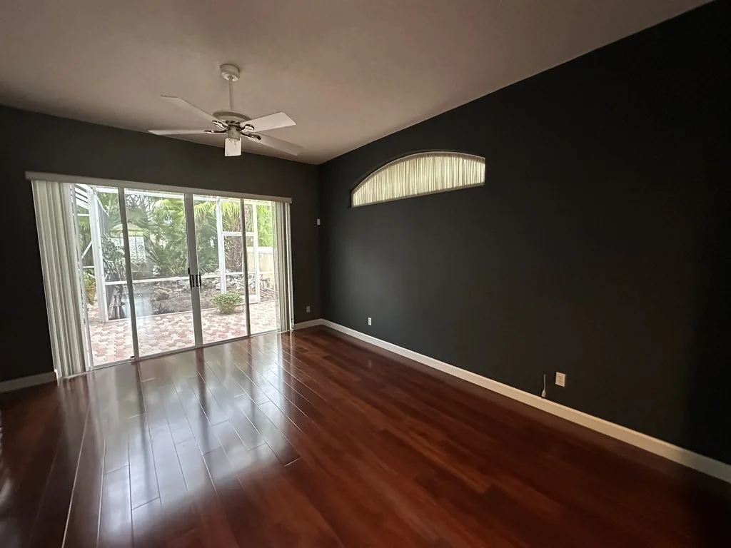 Bedroom after charcoal wall painting white baseboards and warm plank flooring
