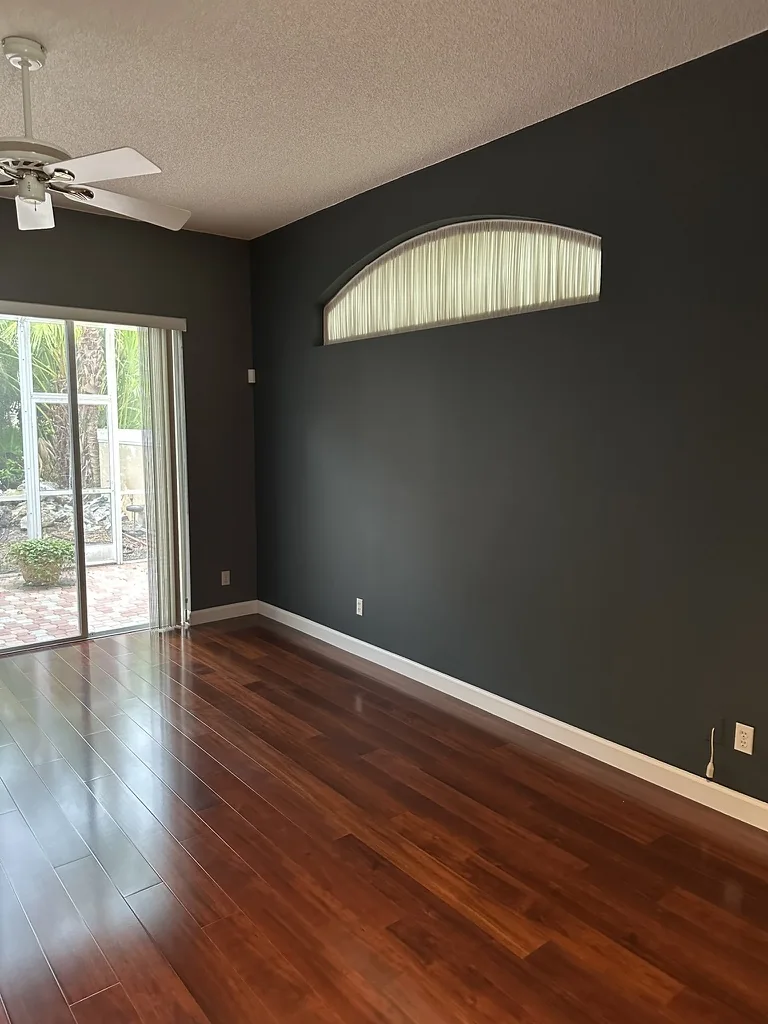 Charcoal painted bedroom wall, white baseboard and engineered wood floor