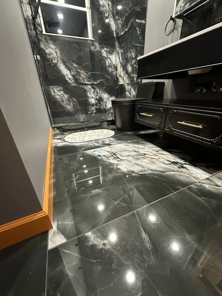 Finished large-format bathroom floor leading toward the mosaic shower