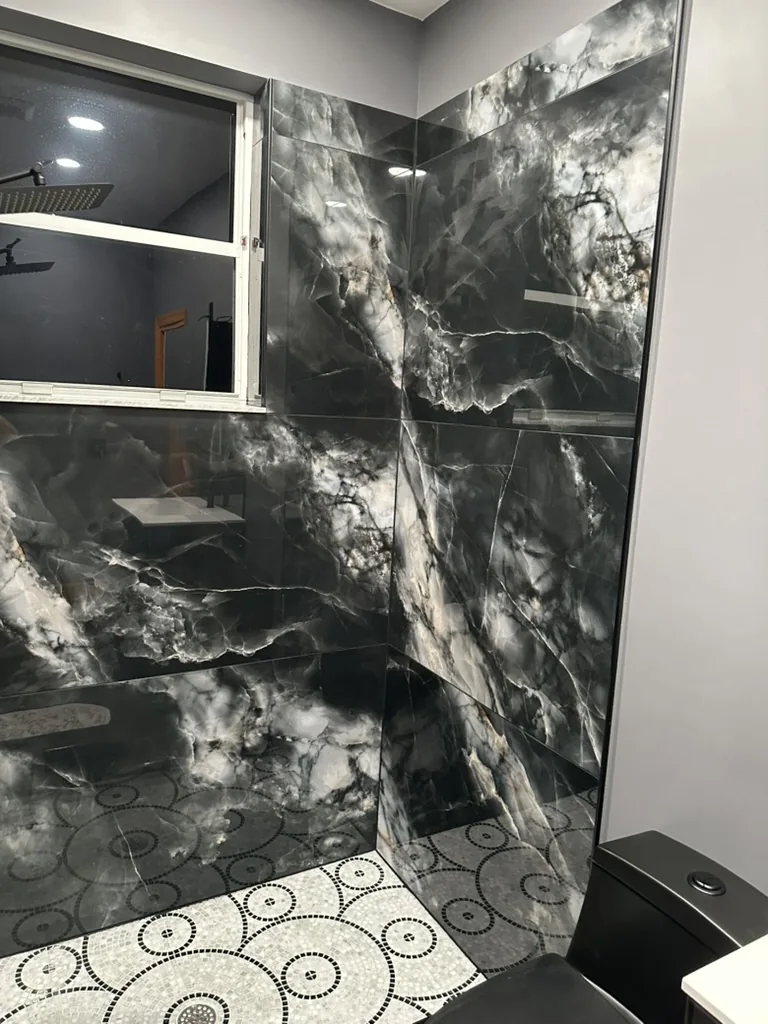 Large-format shower wall tile above the circular mosaic floor