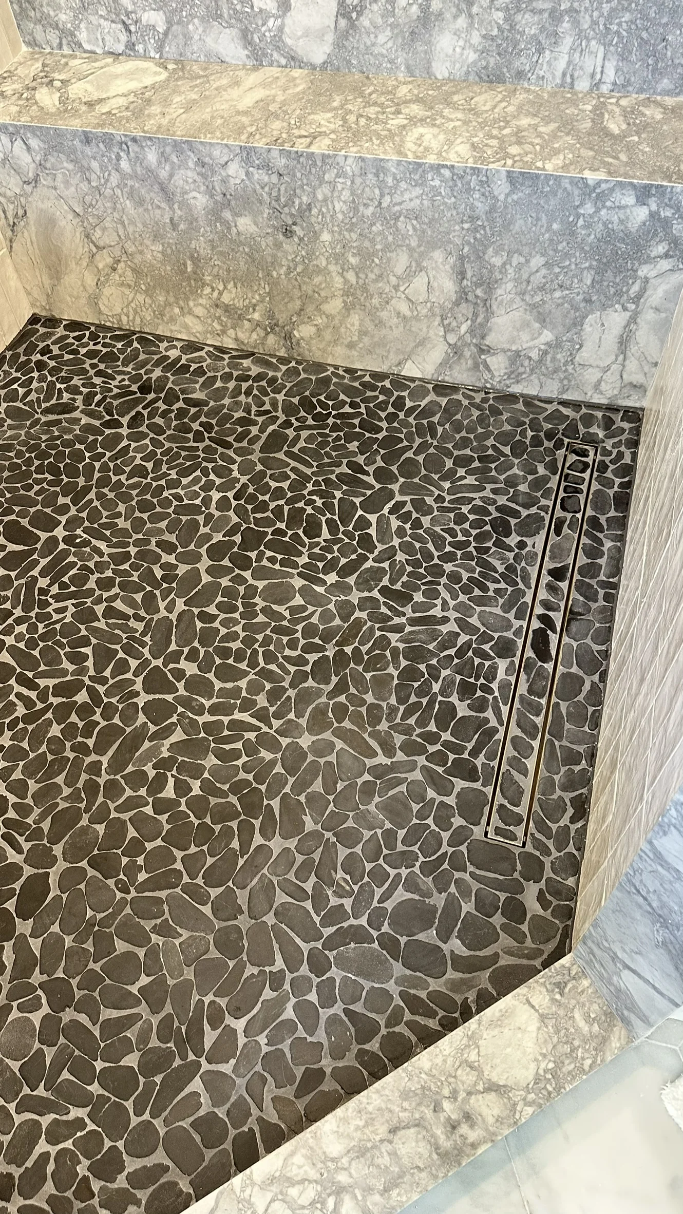 Finished dry pebble mosaic shower floor viewed from the entry