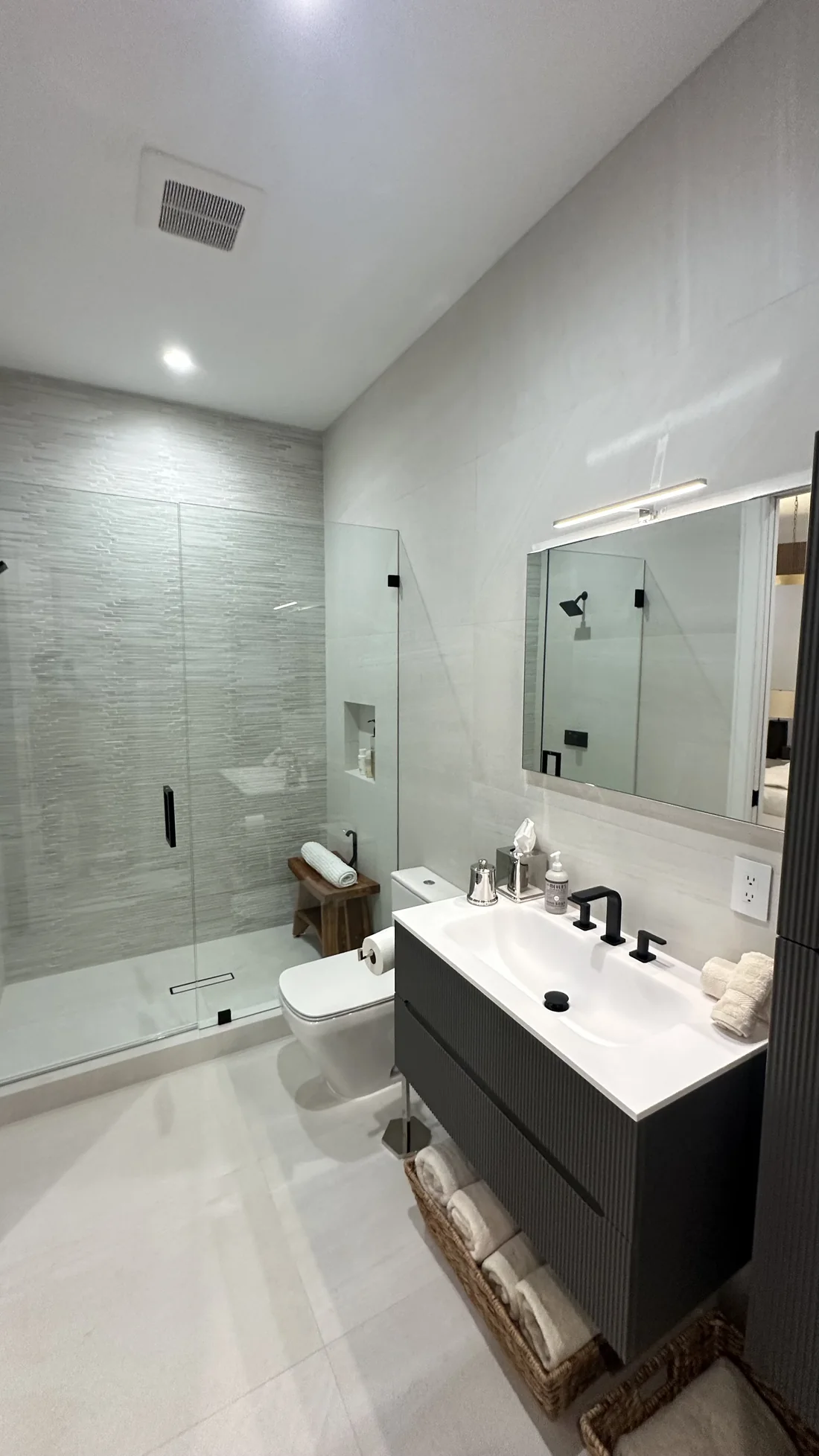 Finished bathroom with large-format tile, frameless shower glass, vanity cabinet, and mirror