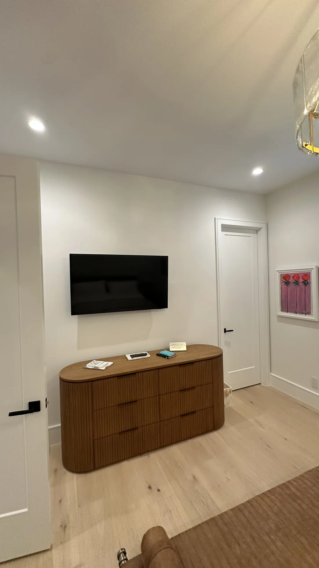 Bedroom with a wall-mounted television above an installed cabinet