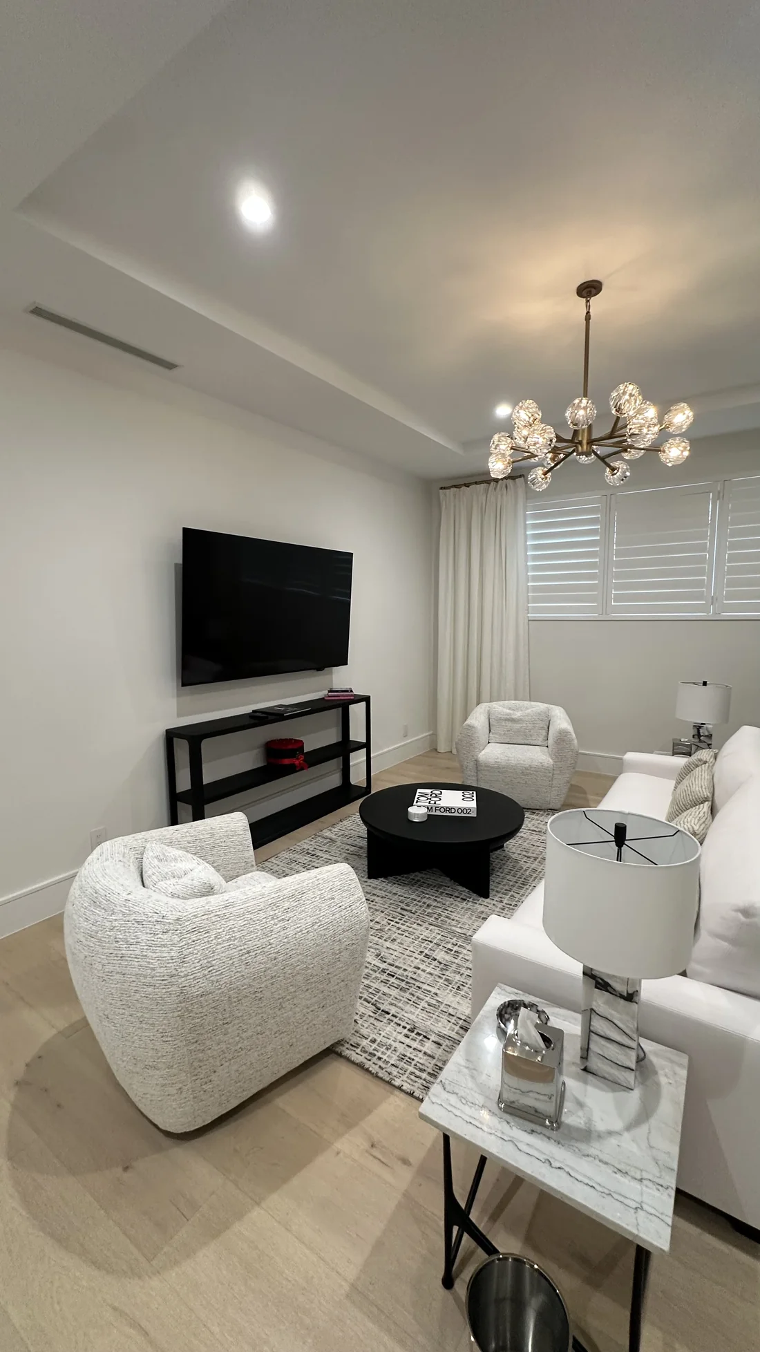 Living room with wall-mounted television, installed console, and full-height curtains
