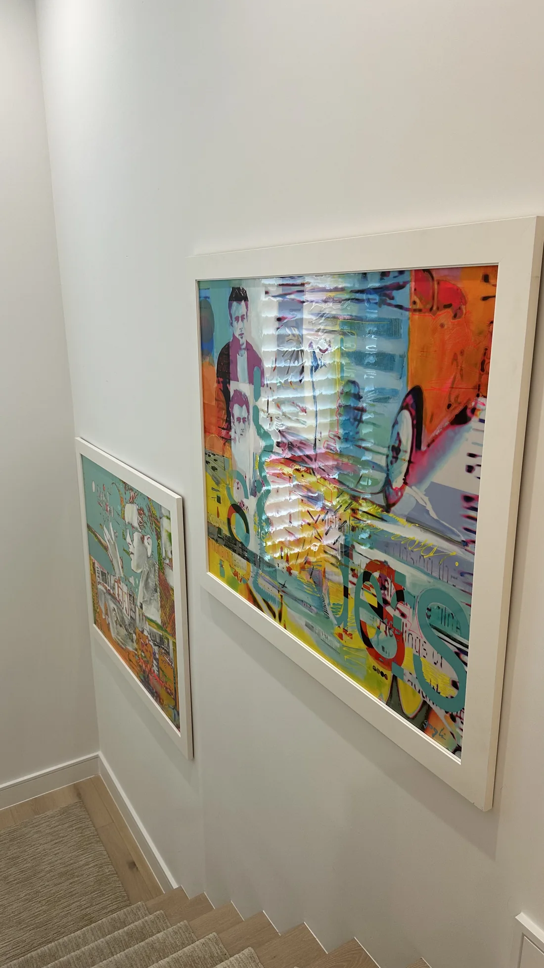 Two colorful framed artworks mounted along a stairway wall