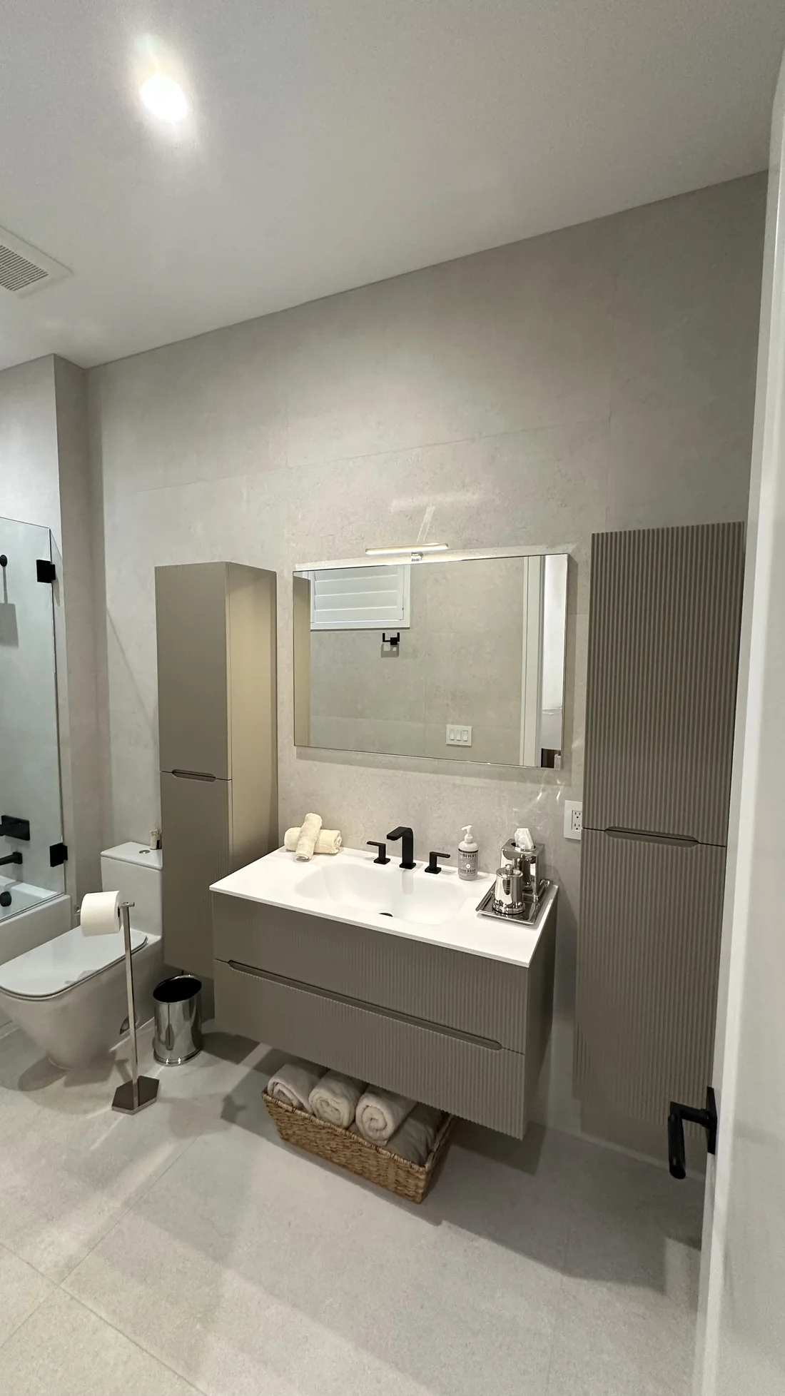 Bathtub with large-format tile, mosaic accent wall, and glass splash panel