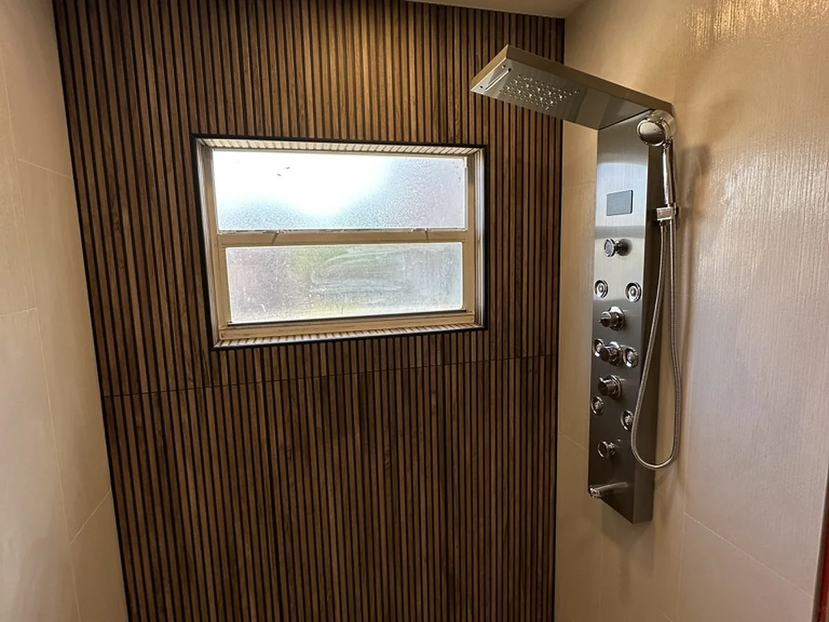 Shower with light tile, vertical wood-look accent tile, and hex mosaic floor